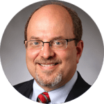 A man with glasses and a beard wearing a suit